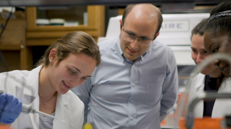 Dr. Alexander Bick in his lab with three women scientists 