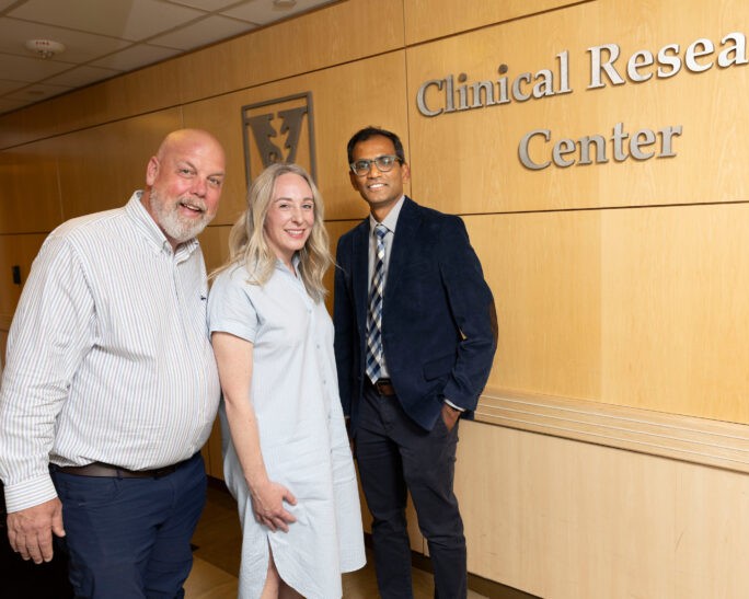 Two male and one female researcher pose in the hallway of the Clinical Research Cetner.