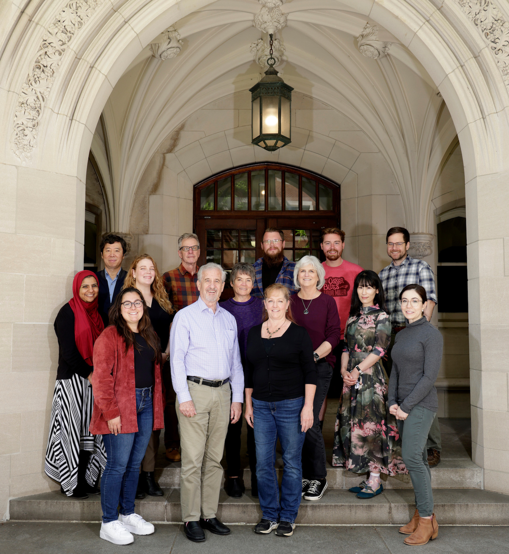 A dozen members of Dr. Dan Roden's research group pose outside an academic building.