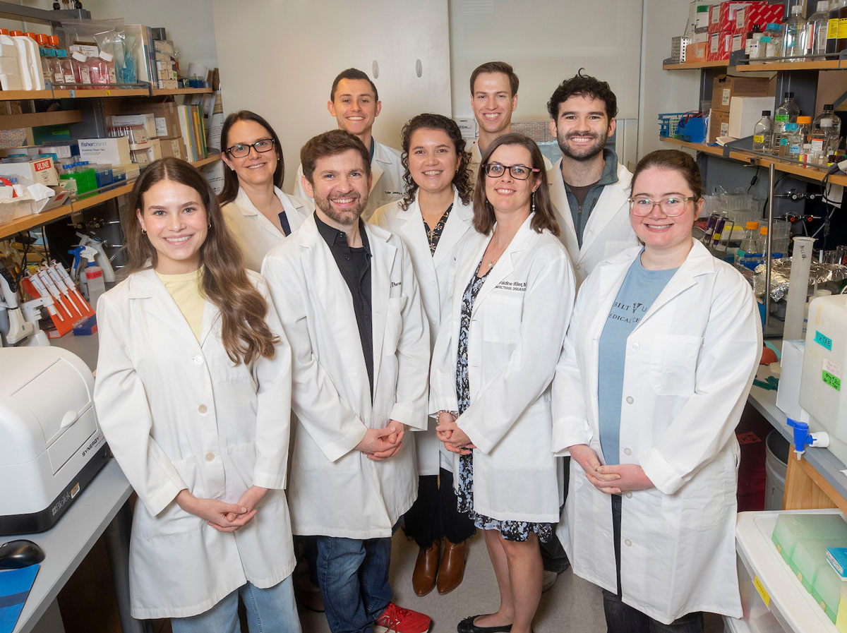 Nine members of a rheumatology research group pose in their lab.