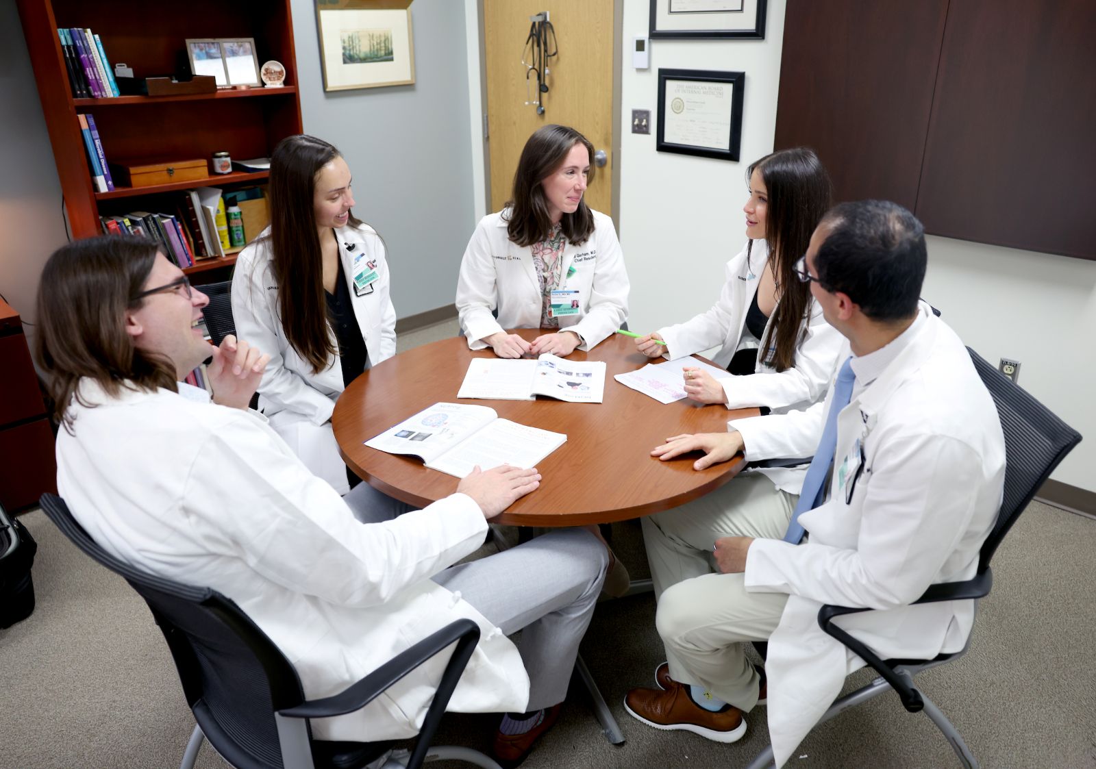 Three female and two male chief residents chat around an office table.