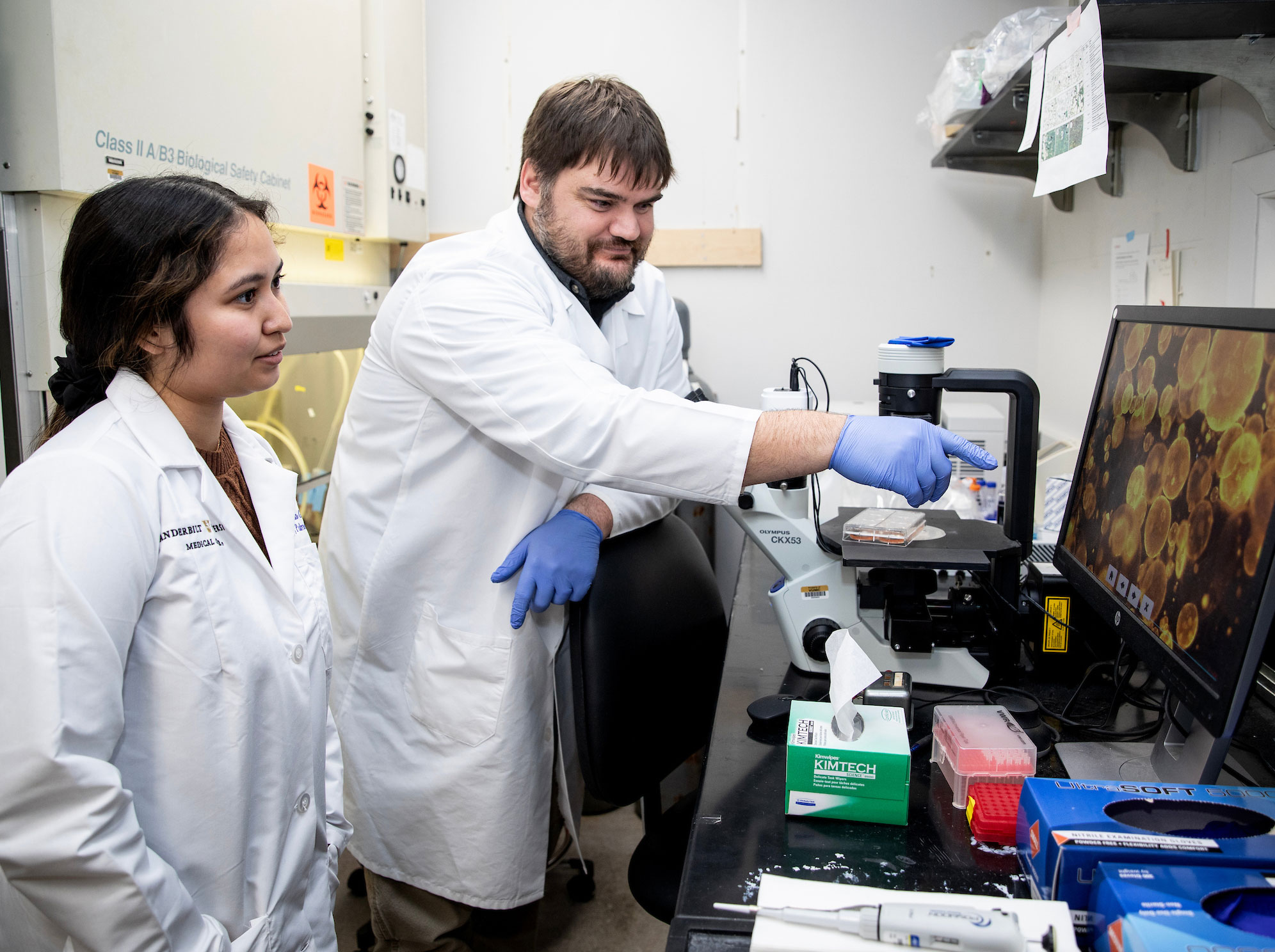 Dr. Jason Gokey chats with a young female researcher while looking at an image on a computer screen in the lab.