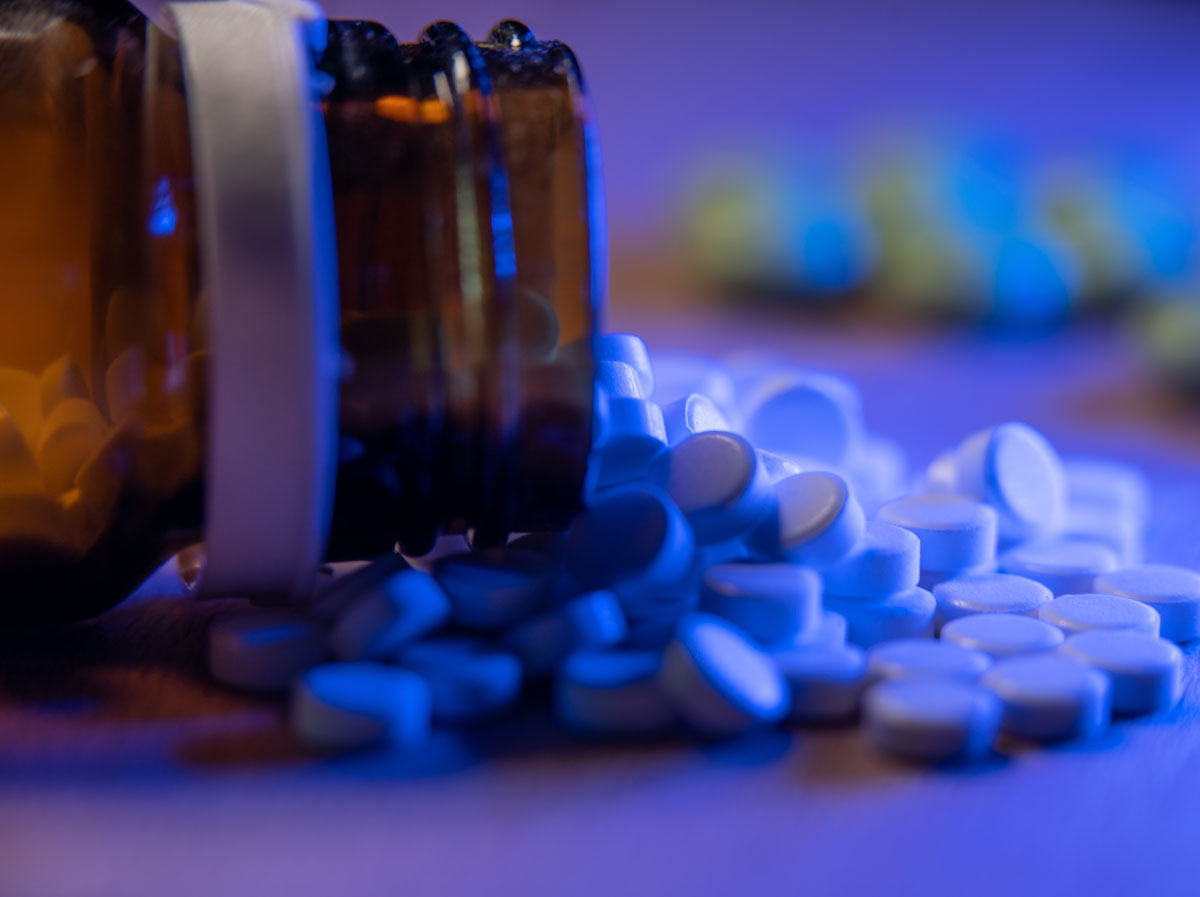 A bottle of white pills spills out on a table.