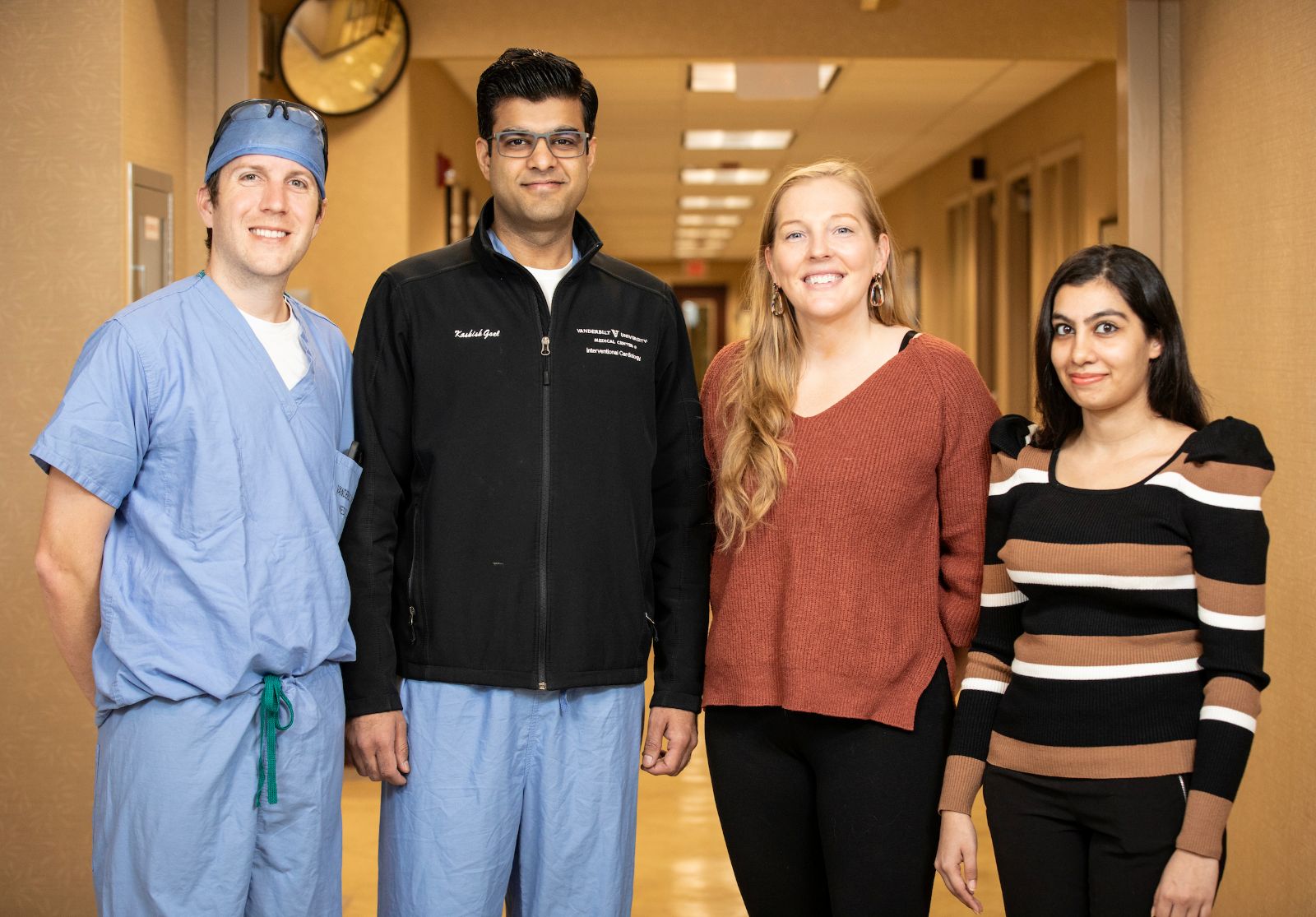A four-person structural heart team, two men and two women, pose in a hospital hallway.