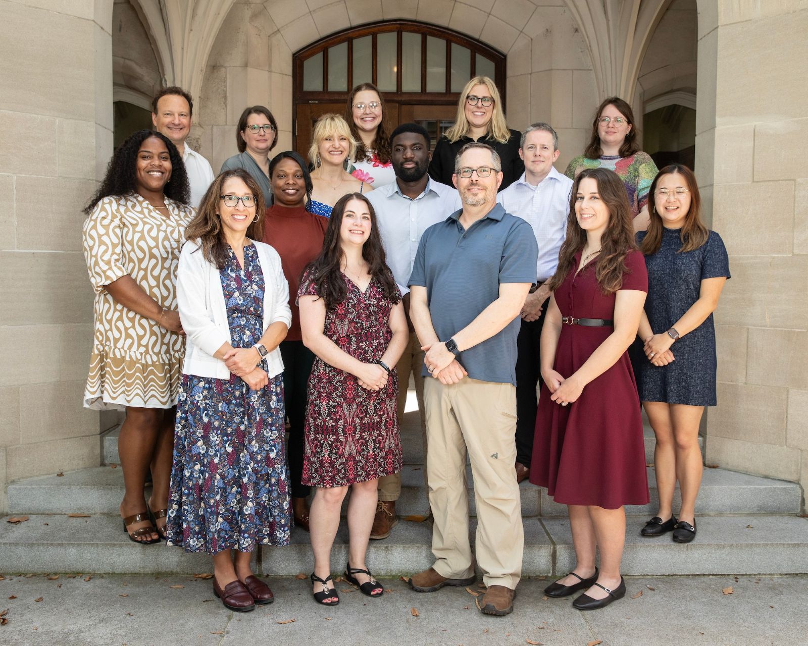 Drs. Todd Edwards and Digna Velez Edwards and 12 lab members pose in front of a Gothic academic building.