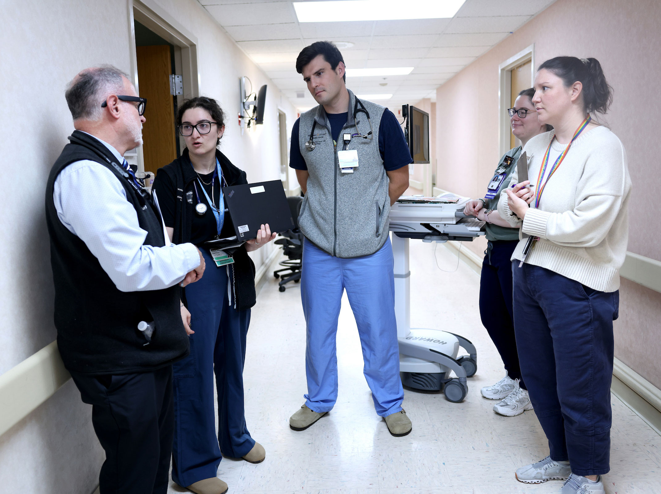 Five medical personnel talk in a hospital hallway.