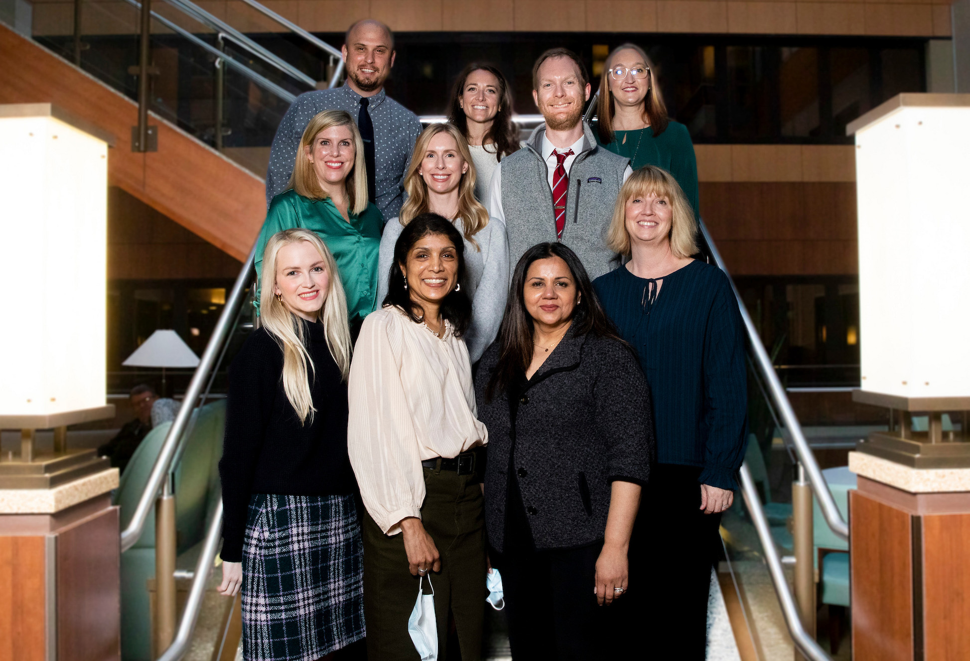 Ten Palliative Care doctors in professional clothes pose on a staircase.