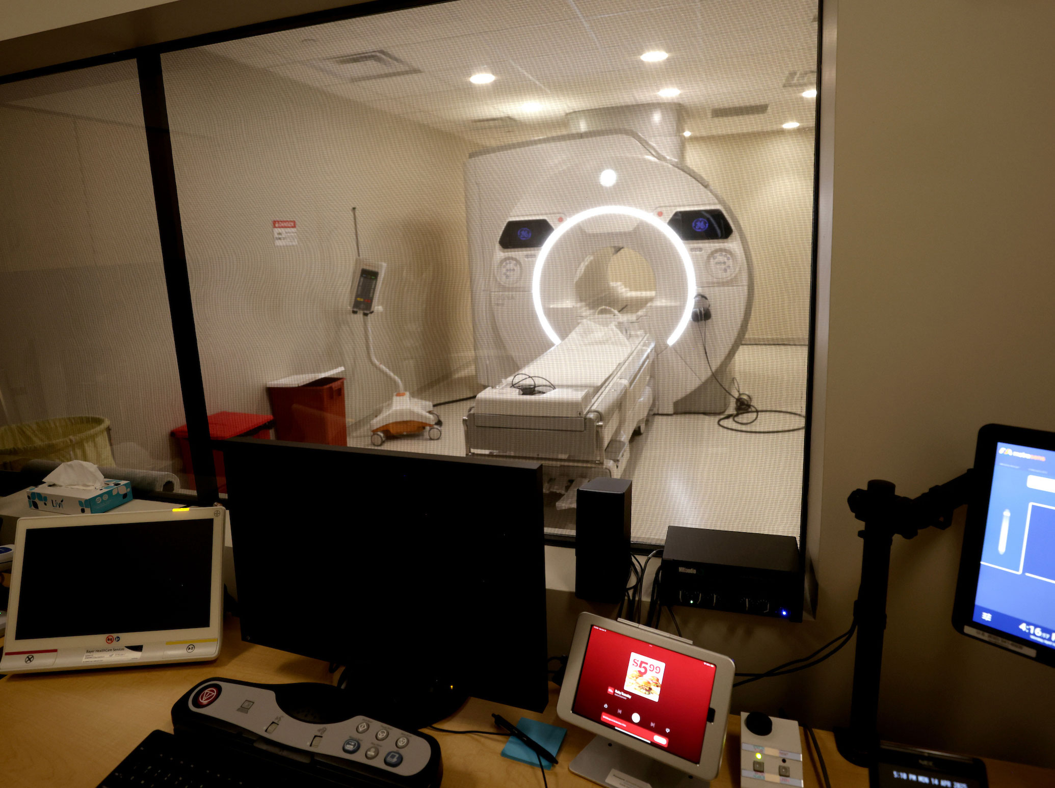 A medical imaging machine is seen through an admin office window.