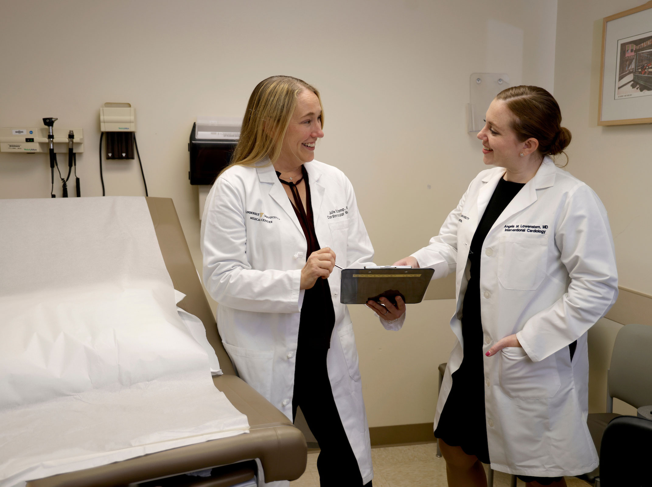 Fellowship program leaders talk while looking at a clipboard in a clinic exam room.