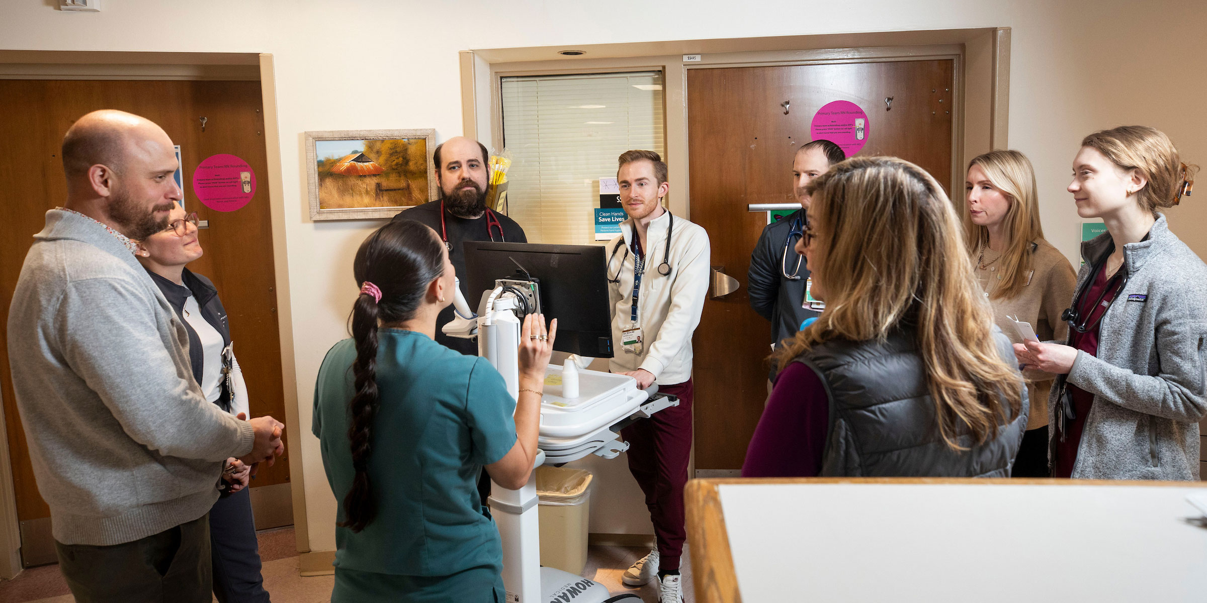 A group of about 10 palliative care physicians and personnel  meet in a hospital hallway.