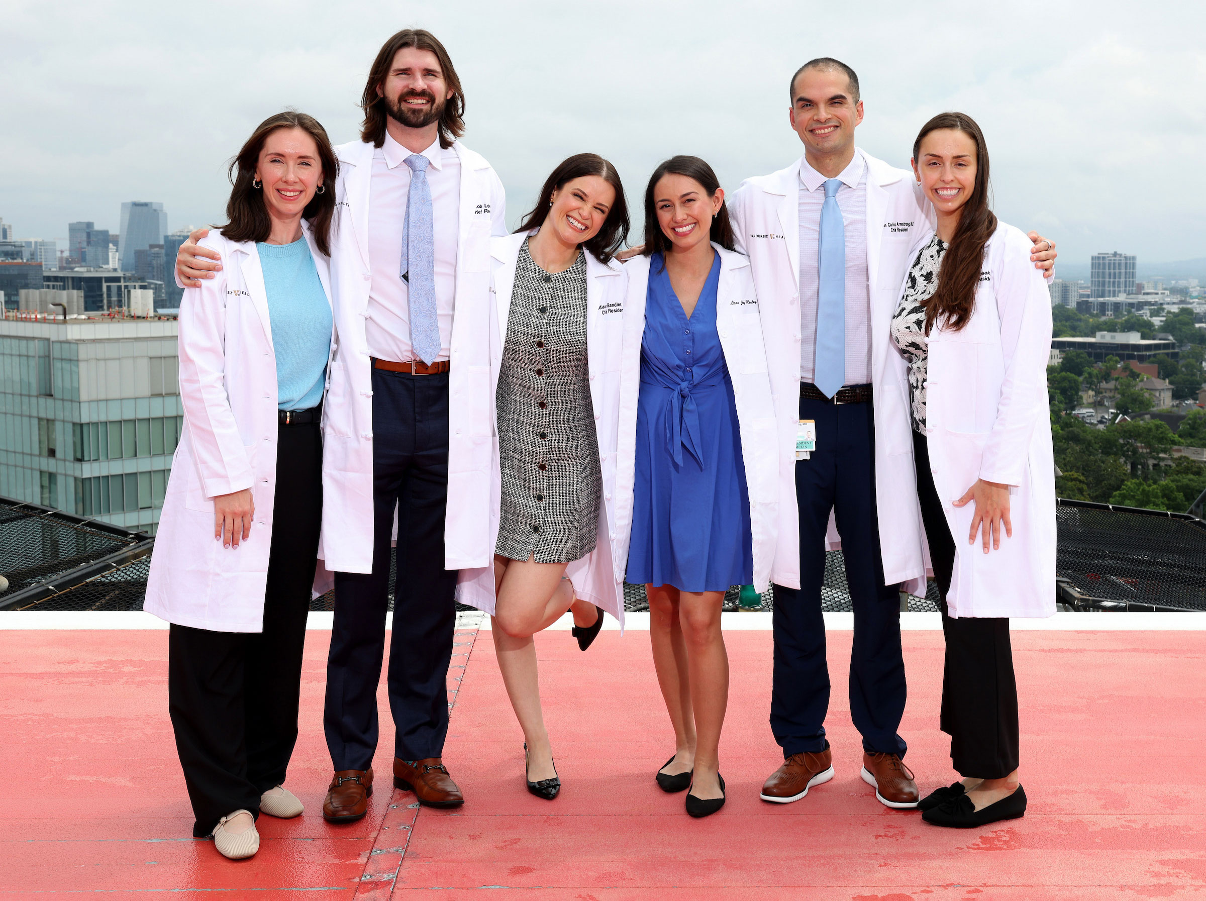 Six Internal Medicine chief residents in white lab coats pose on the Vanderbilt hospital helipad with the Nashville skyline in the background.