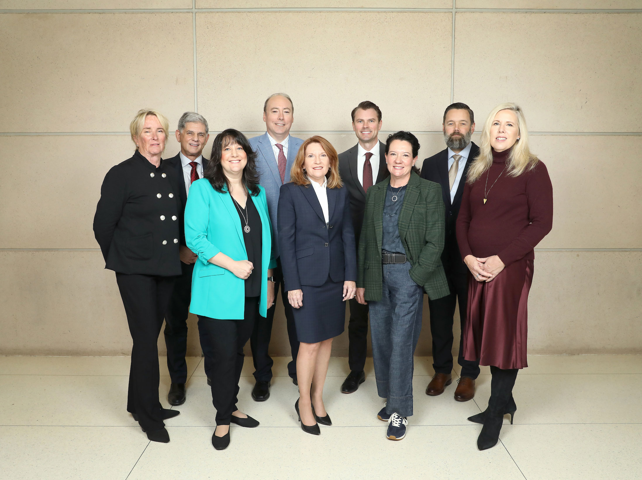 About 10 medical executives in business attire pose for a photo outdoors.