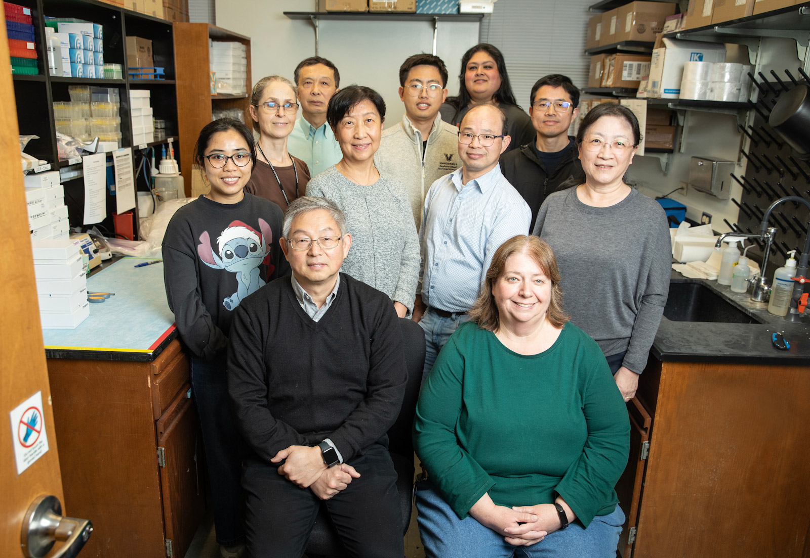 A dozen members of the Dr. Qiuyin Cai Lab pose in the research lab.