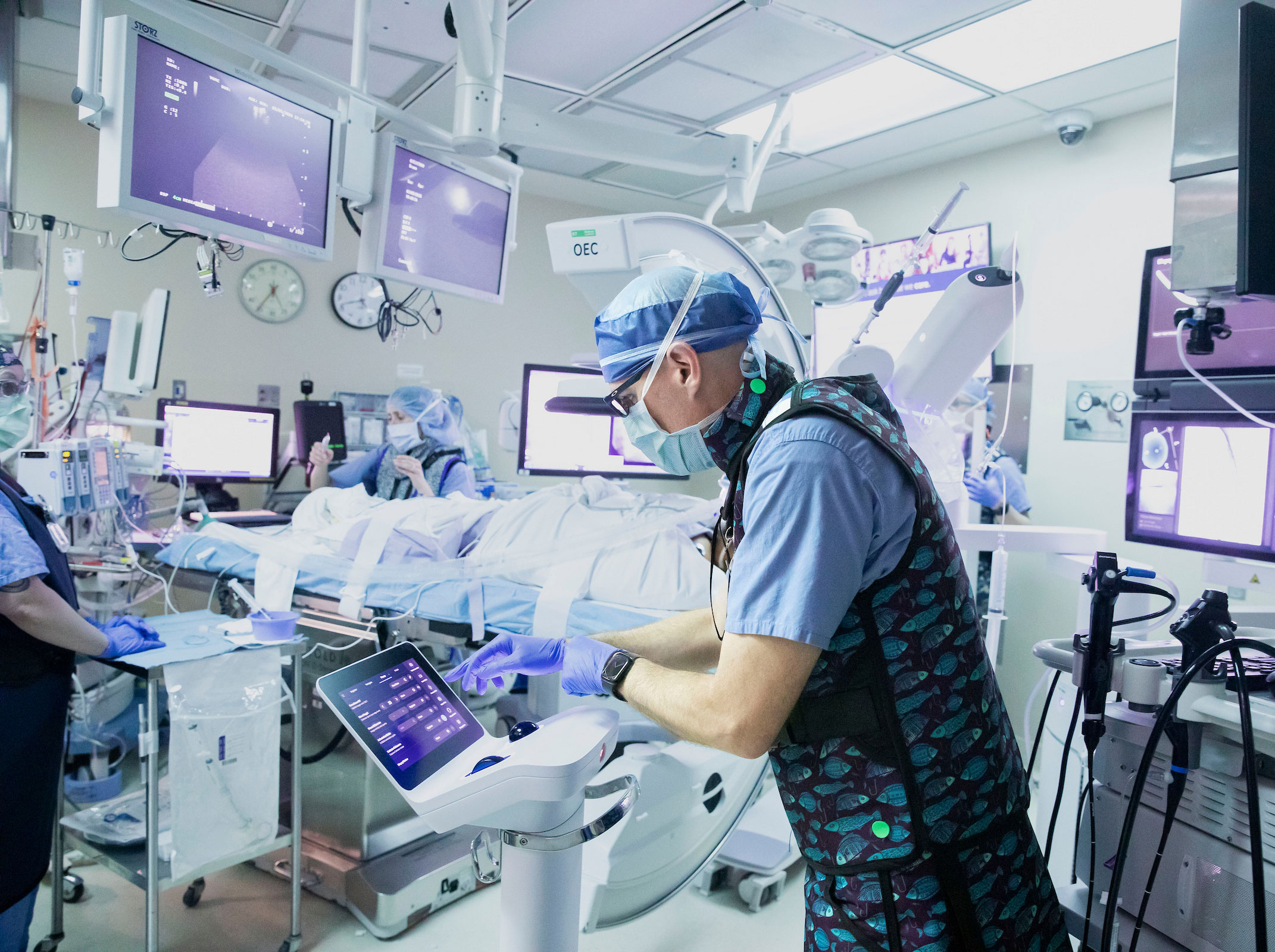 Three doctors in full scrubs and masks prepare in the operating room for a pulmonary procedure.