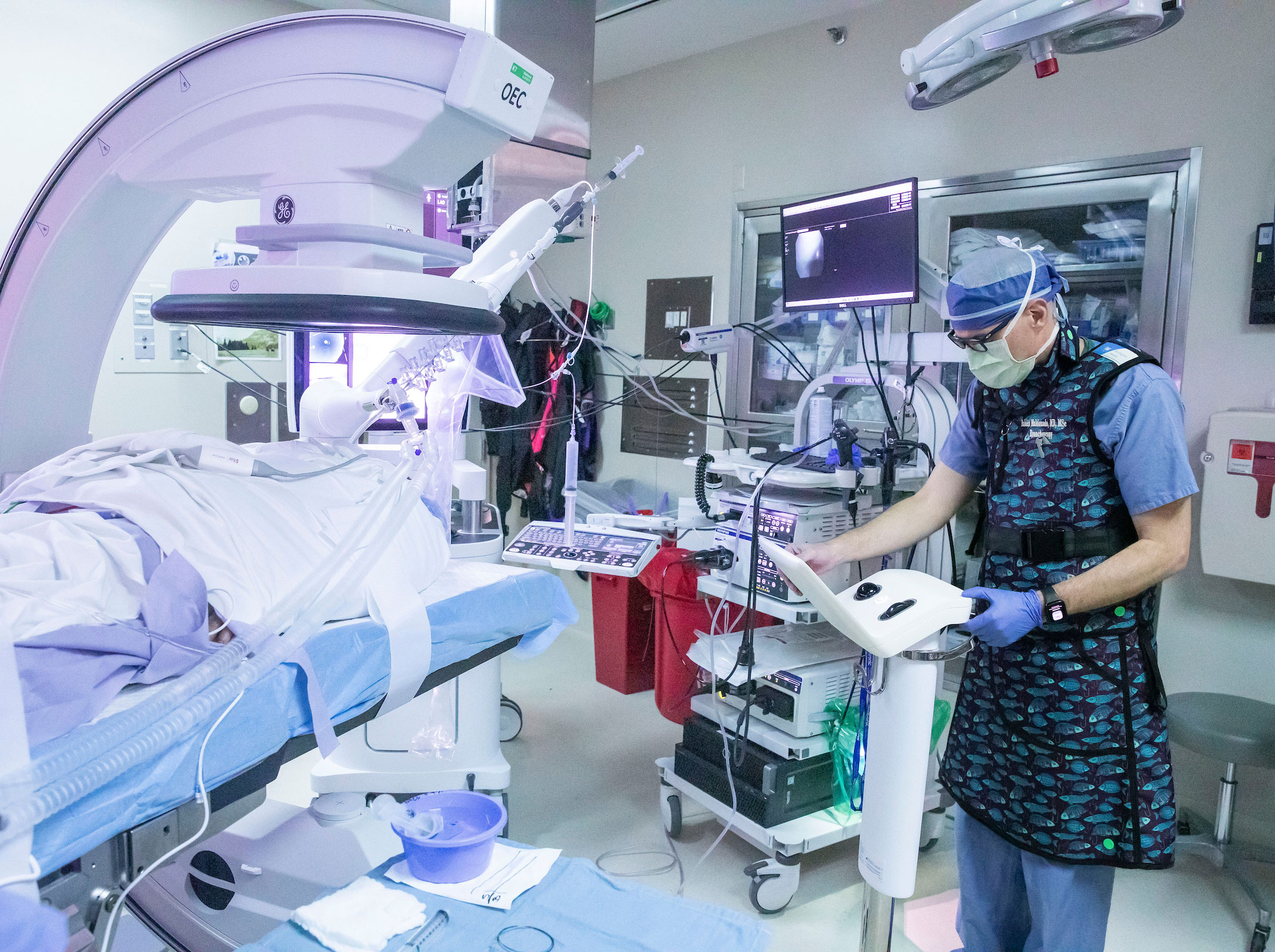 A male doctor in full scrubs and mask prepares in the operating room for a pulmonary procedure.
