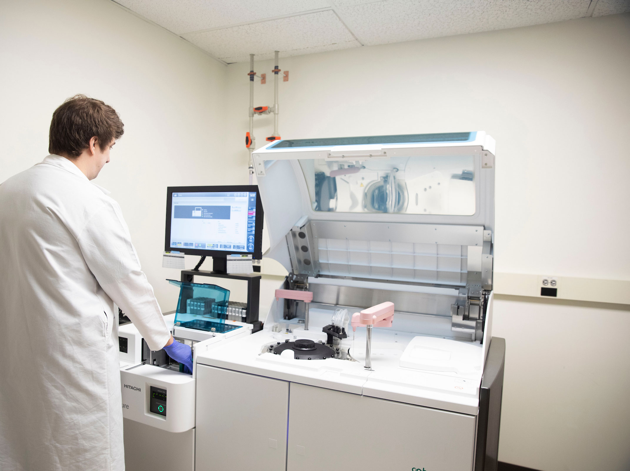 A white male in a white lab coat works with an instrument in a cardiology research lab.
