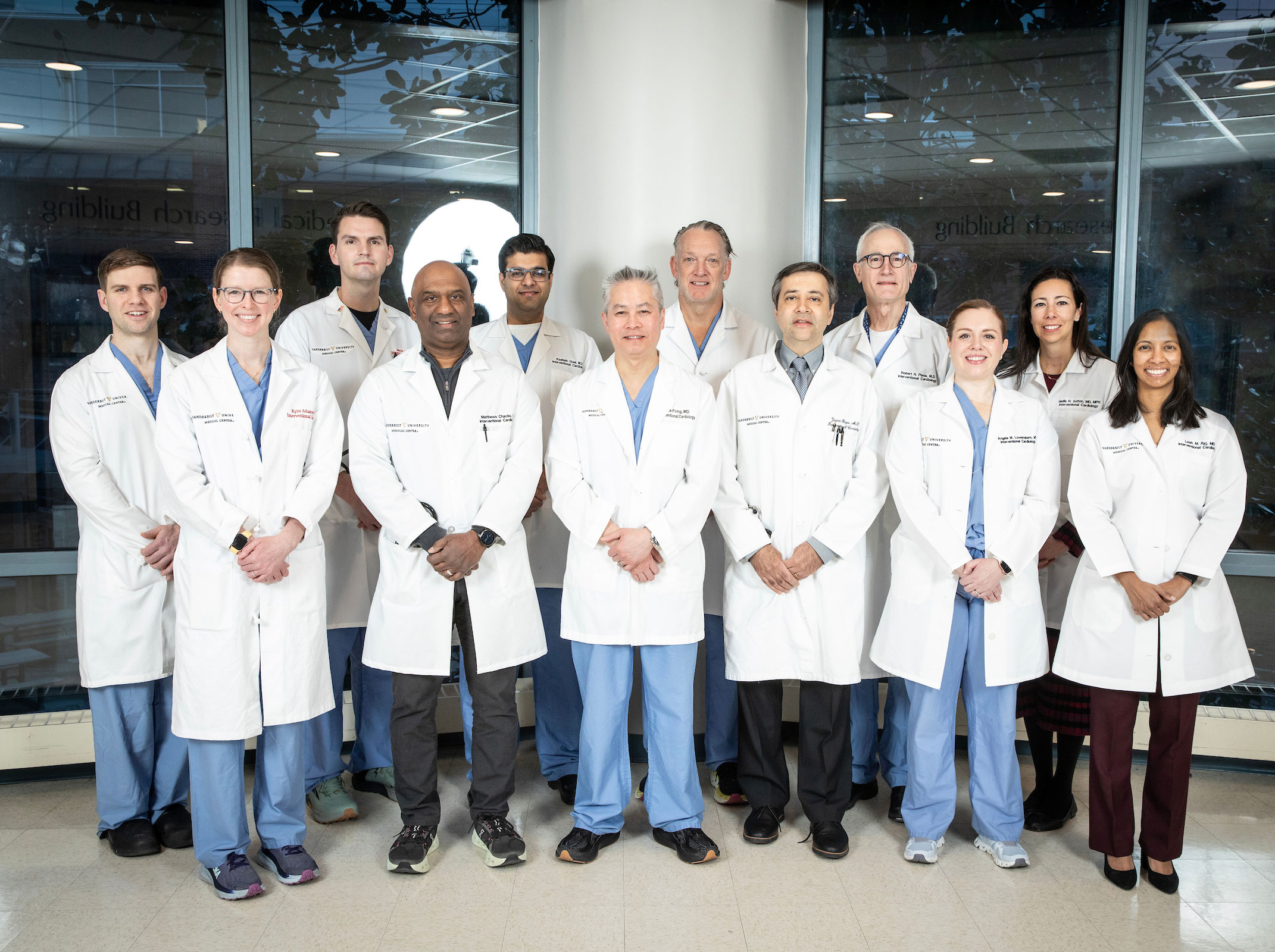 About 15 doctors in white lab coats pose in a hospital atrium.