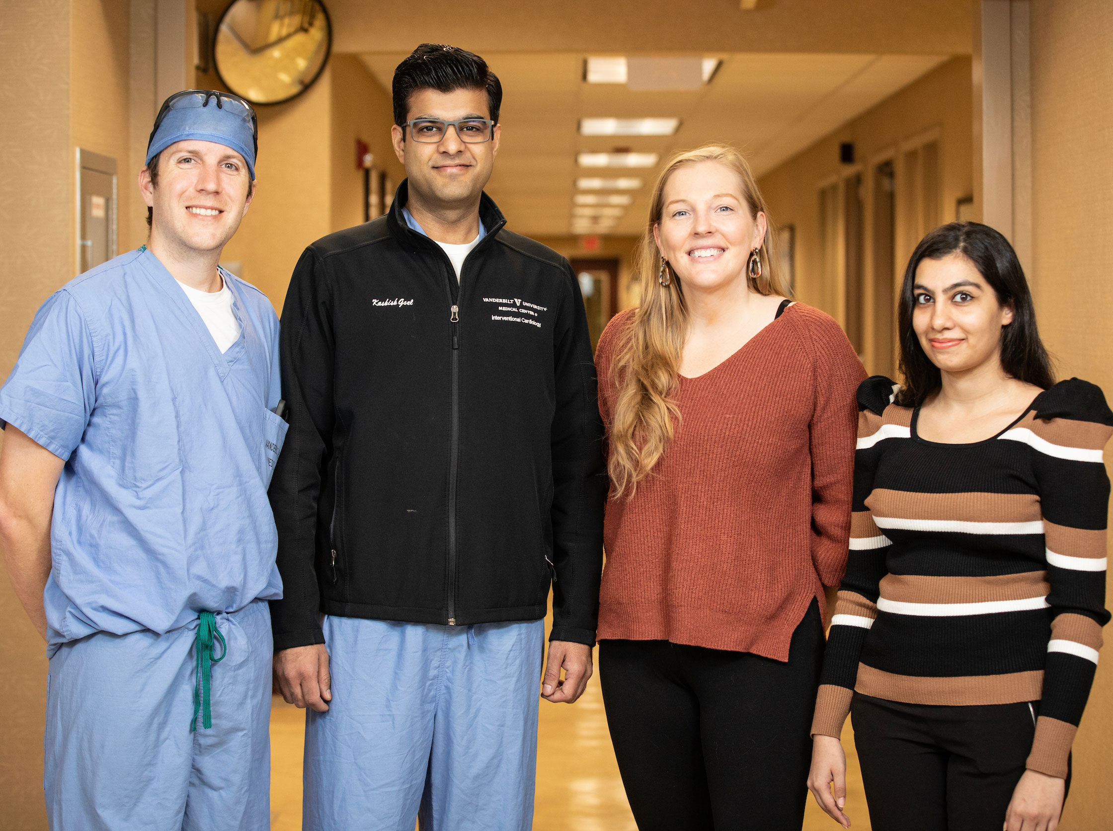 A four-person structural heart team, two men and two women, pose in a hospital hallway.