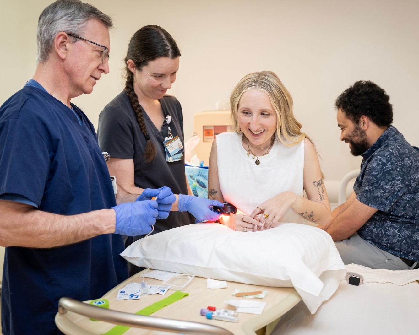 Nurses assist a female clinical trials patient in an exam room.