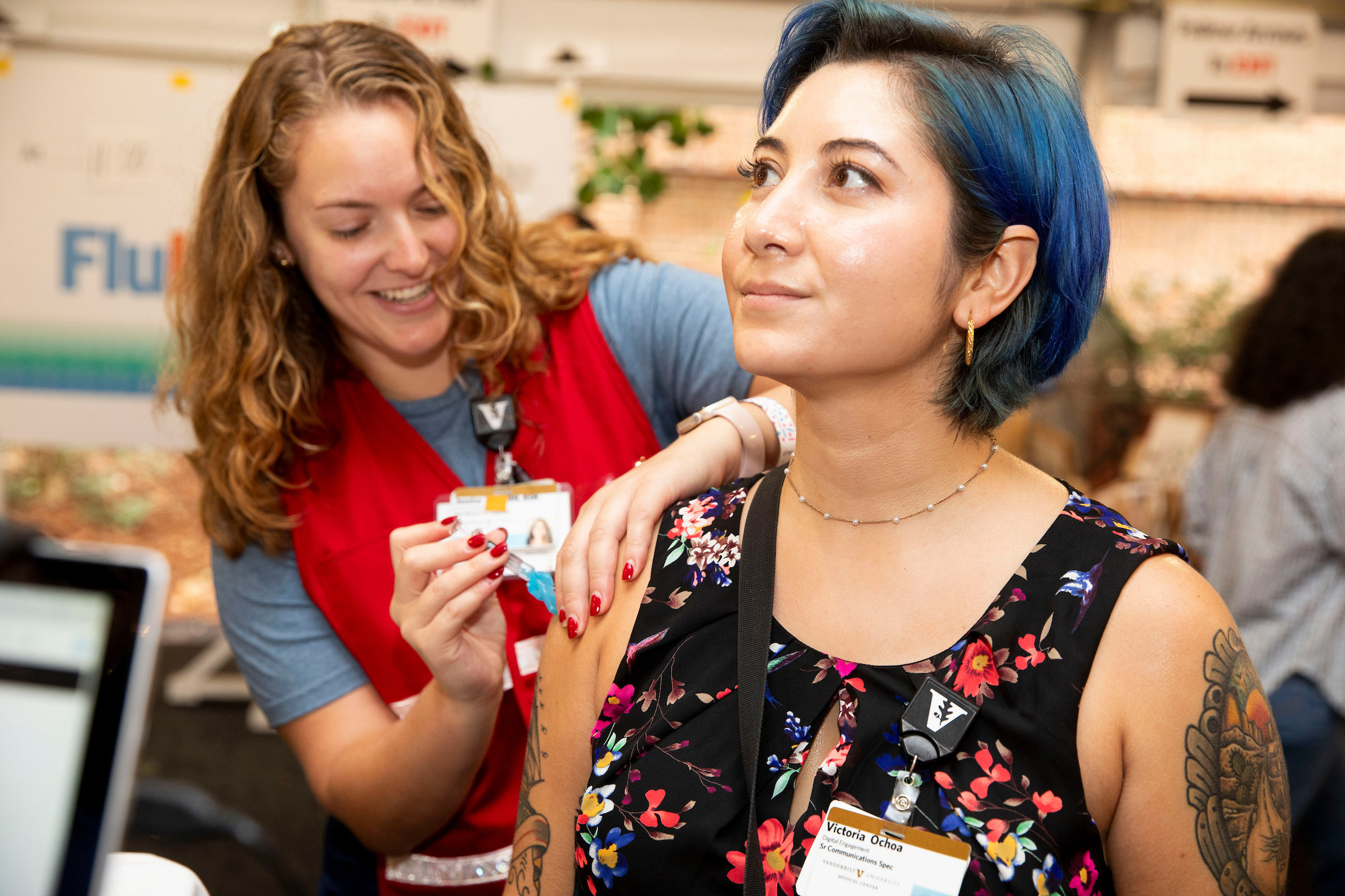 A young woman with blue hair and a tattoo gets a flu vaccine.
