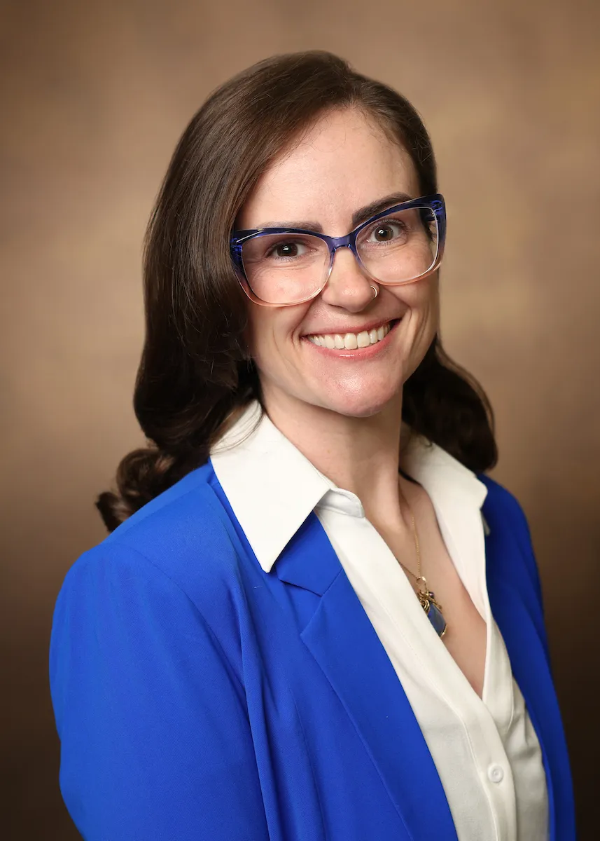Dr. Megan Dupuis headshot, a white female physician in a blue cardigan and glasses.