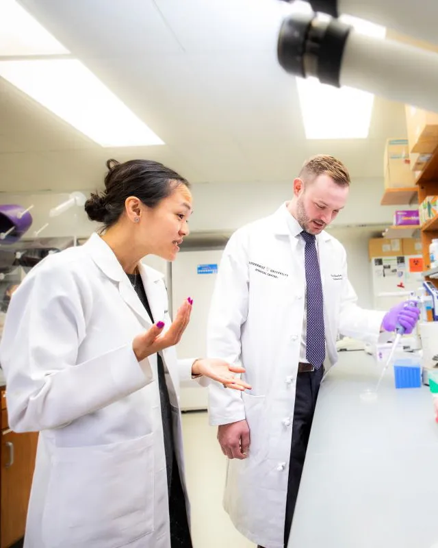 An Asian female research physician and a white male research physician work together in the lab.